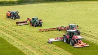 Ein Bild diverser Futtererntemaschinen (Mähwerk, Wender, Schwader und Ballenpresse) aus dem Hause KUHN.