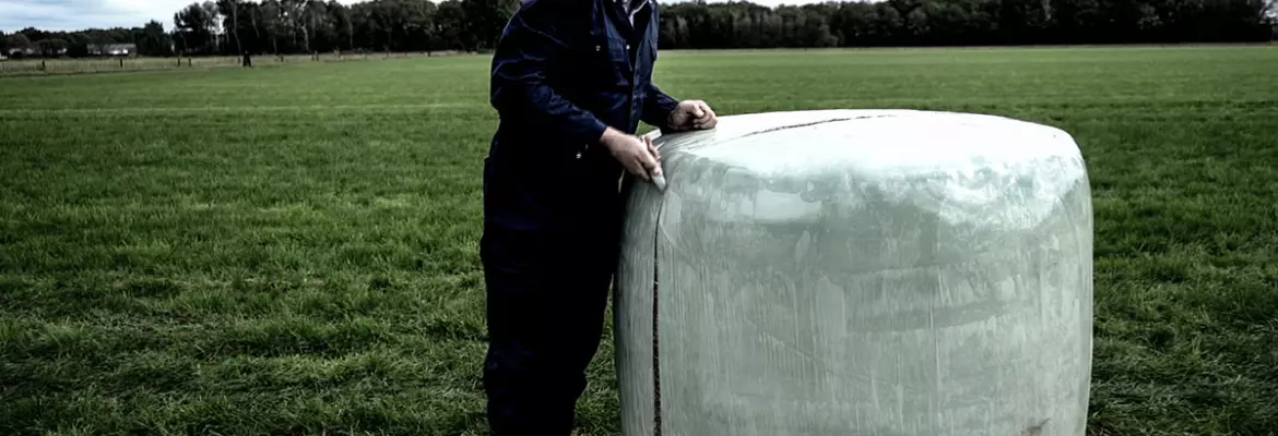 Photo illustrant un agriculteur qui ouvre une balle enrubannée