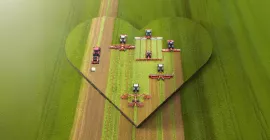 Das Keyvisual der KUHNaktuell. Herbstrasen 2026, welches KUHN Futtererntemaschinen in einem Herz auf dem Feld darstellt.
