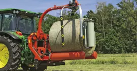 Wickler RW 1200 für den Dreipunktanbau beim Wickeln eines Rundballens auf dem Feld.
