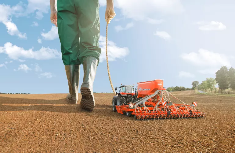 Eine Darstellung der ESPRO, einer gezogenen Universal-Drillmaschine der Firma KUHN, die wie ein Spielzeug von einem großen Menschen bewegt wird.