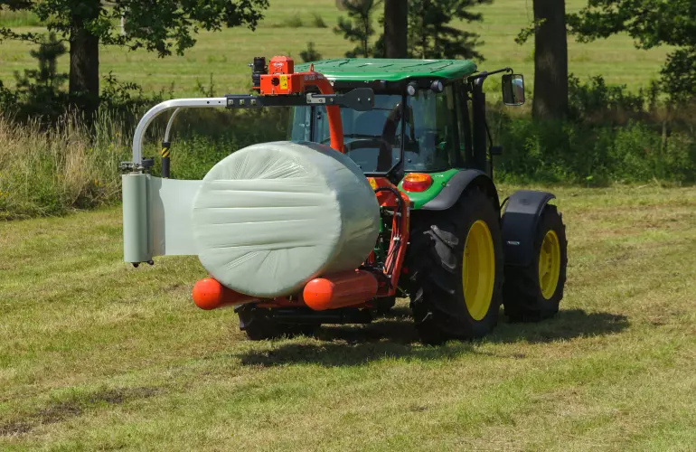 Wickler RW 1200 für den Dreipunktanbau beim Wickeln eines Rundballens auf dem Feld.