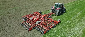 Ein Bild eines HIGHLANDER Zinkengrubbers der Firma KUHN im Feldeinsatz.