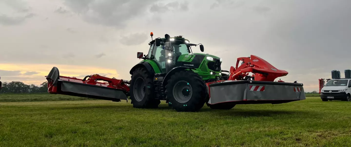 Ein Bild eines Traktors mit Frontmähwerk und Heckmähwerkskombination von der KUHN ON TOUR - Futterernte und Pressen 2024.