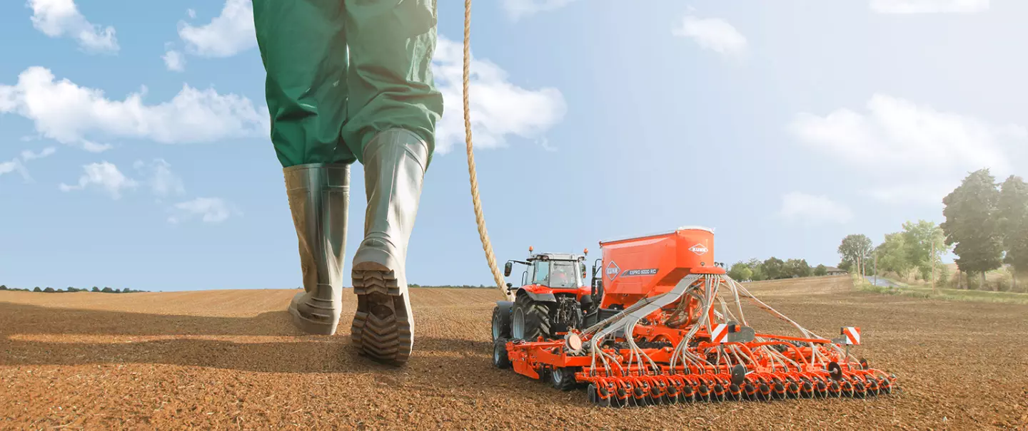 Eine Darstellung der ESPRO, einer gezogenen Universal-Drillmaschine der Firma KUHN, die wie ein Spielzeug von einem großen Menschen bewegt wird.