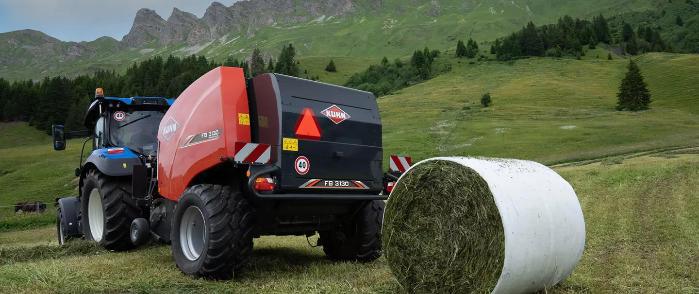 Festkammer-Rundballenpresse KUHN FB 3130 mit Folienbindung beim Pressen von Rundballen in den Bergen