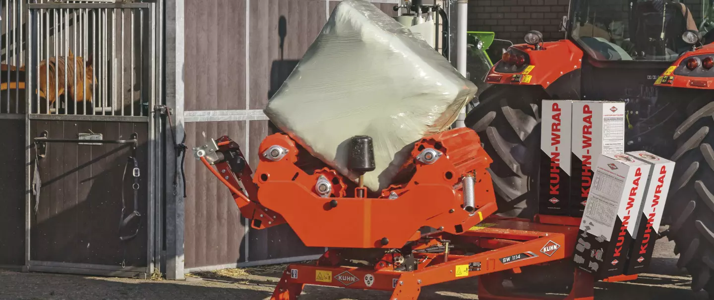 Quaderballenwickler SW 1114 beim ortsfesten Wickeln vor einem Pferdestall.