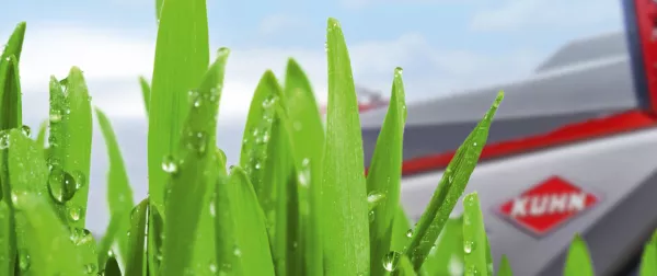 Das Keyvisual der KUHNaktuell. Pflanzenschutztechnik 2026, welches eine KUHN Feldspritze hinter Gras mit Tropfen drauf darstellt.