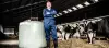 Photo illustrant un agriculteur dans une étable avec une botte de foin enrubanné pour son élevage.