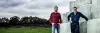 Photo illustrant un agriculteur devant son stock ses bottes de foin rondes. 